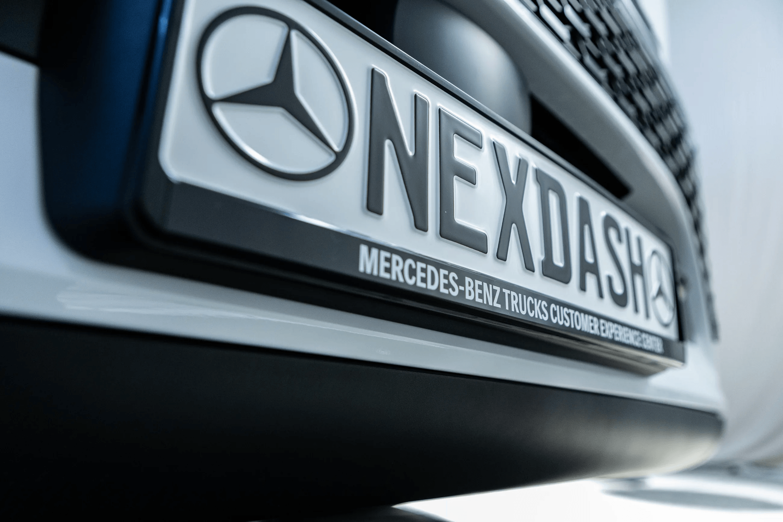 Kennzeichenträger mit NEXDASH-Schriftzug an einem Mercedes-Benz eActros